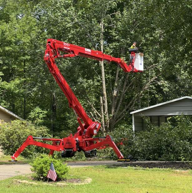 Stingray's red spider lift reaching over a front yard to take down a tree